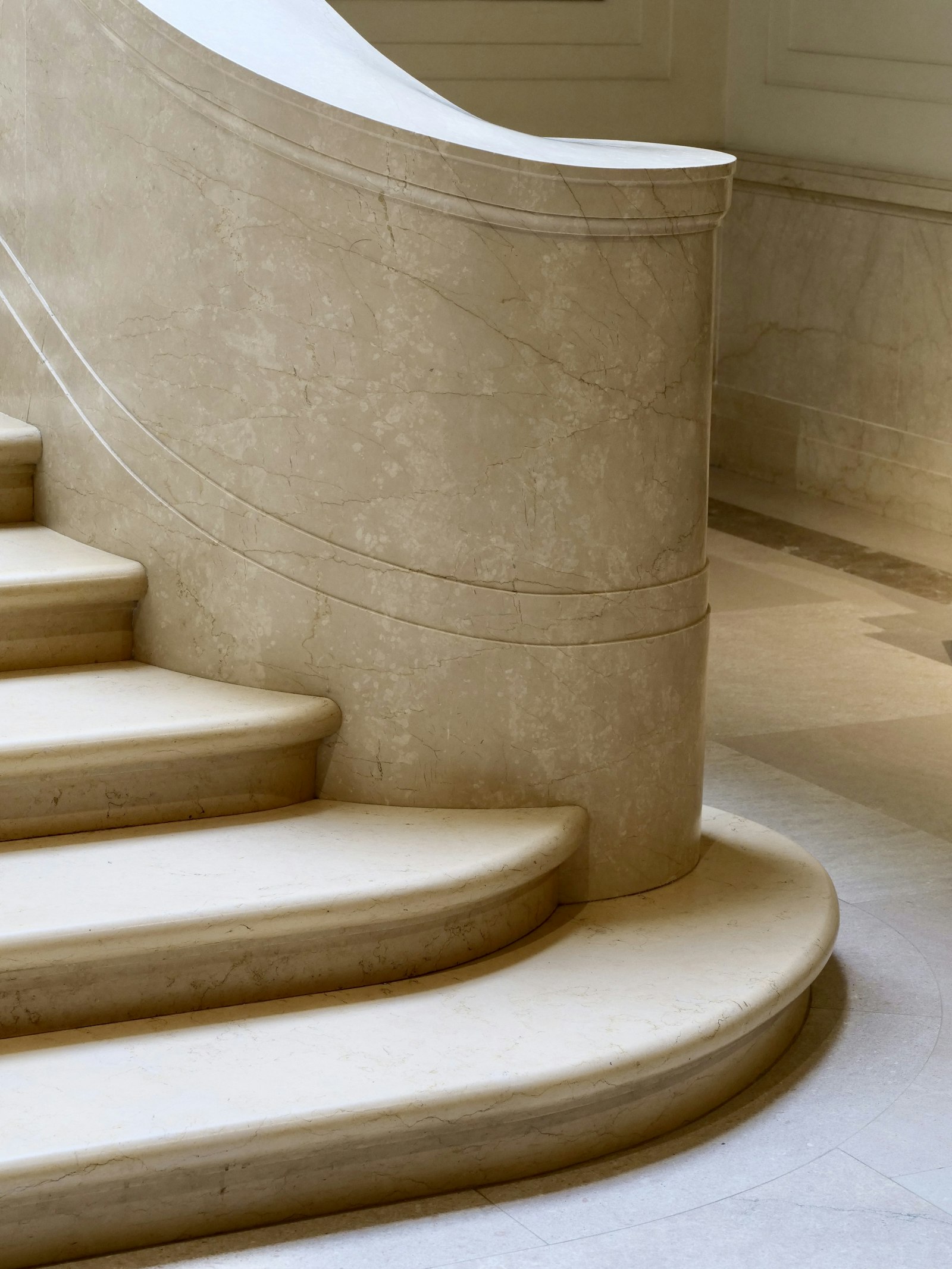 A curved cream marble staircase in soft daylight — Scent Works. Spraying a Nice Smell Around Doesn't.